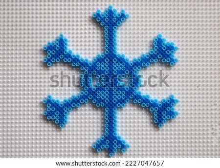 Blue snowflake made from hama beads. Children's crafts on a white background.