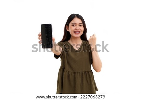 Happy young asian woman standing while showing a blank screen of her cell phone. Isolated on white