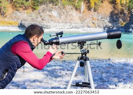 Amateur astronomer adjusts optical for viewing at sky through telescope.Mountain explorer in nature looks at the horizon through a telescope, outdoor exploring lifestyle concept with beautiful view. Royalty-Free Stock Photo #2227063453