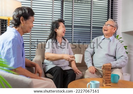 Group of senior friends in living room talking and laughing together.