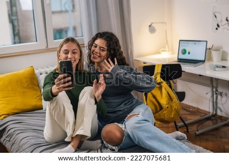 Two friends answering video call at dormitory Royalty-Free Stock Photo #2227075681