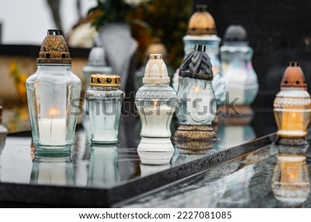 All Saints' Day and burning candles and flowers on the graves.Candles on graves symbolize the memory of the dead on November 1.Catholic cemetery during All Saints' Day.Selective focus.Closeup. Royalty-Free Stock Photo #2227081085