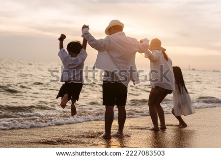 Happy asian family jumping together on the beach in holiday vacation. Silhouette of the family holding hands enjoying the sunset on the sea beach. Happy family travel, trip  family holidays weekend.