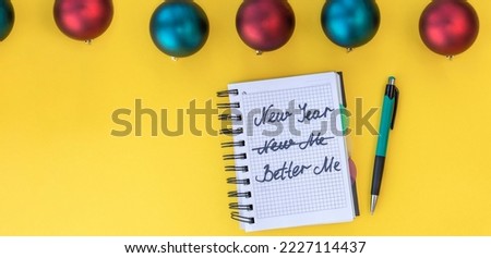 banner with Writing in a notebook New year, new me on yellow background with Christmas balls. Happy new year quote. Top view. Flat lay