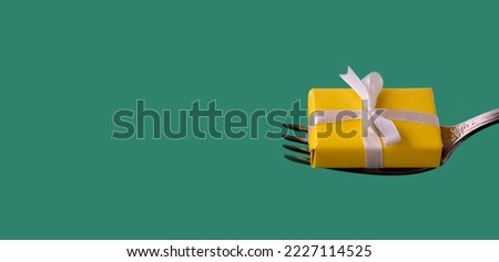 banner with yellow gift with white ribbon lies on fork on green background. holiday, christmas or birthday concept. copy space,