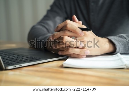 Close up of man clasped hands clenched together on table, businessman preparing for job interview, concentrating before important negotiations, thinking or making decision, business concept Royalty-Free Stock Photo #2227114709
