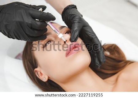 female lips, lip augmentation procedure. A syringe near a woman's mouth, injections to increase the shape of the lips Royalty-Free Stock Photo #2227119255
