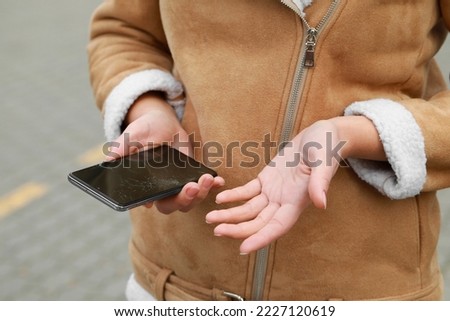 Woman holding damaged smartphone outdoors, closeup. Device repairing