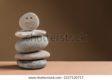 Stack of stones with drawn happy face on table against dark beige background, space for text. Zen concept