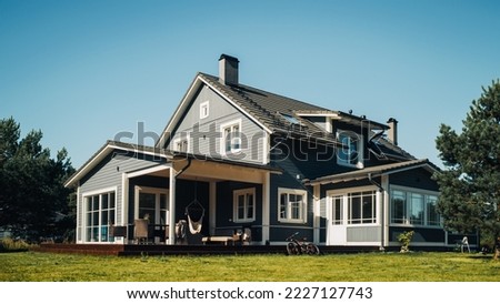 Landscape Shot with a Big Gray Residential Home on a Scenic Day with Clean Blue Sky. House in a Suburban Area with Majestic Nature. Low Angle Shot. Royalty-Free Stock Photo #2227127743