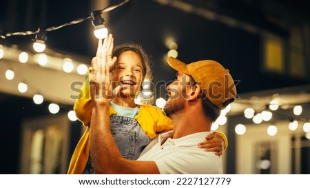 Proud Handsome Father Helping His Little Beautiful Daughter to Change a Lightbulb in Fairy Lights Backyard Installation at Home. Father and Daughter High Five and Celebrate Successful Fix. Royalty-Free Stock Photo #2227127779