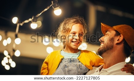 Proud Handsome Father Helping His Little Beautiful Daughter to Change a Lightbulb in Fairy Lights Backyard Installation at Home. Father and Daughter Repair Lights on a Porch. Royalty-Free Stock Photo #2227127805