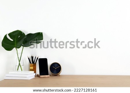 Comfortable workplace with wooden desk near white wall at home Royalty-Free Stock Photo #2227128161