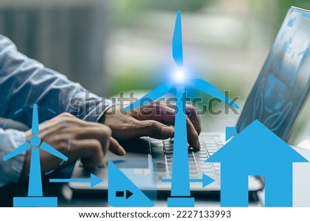 Windmill and energy house icons in front of businessman working with laptop, showing various energy symbols The concept of clean renewable energy sources. energy from the environment