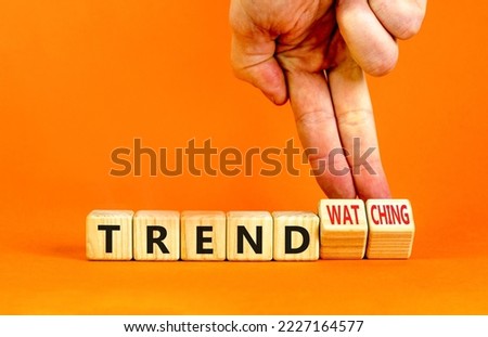 Trend or trendwatching symbol. Concept words Trend and trendwatching on wooden cubes. Businessman hand. Beautiful orange table orange background. Business trend or trendwatching concept. Copy space.