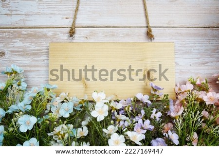 Empty space of Wooden sign hanging with rope and artificial flower decoration on wooden background