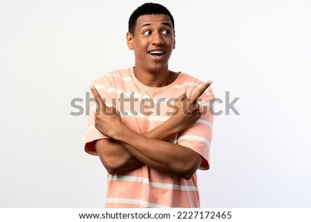 Happy excited young man looking away pointing up with fingers hand gesture at copy space advertising new promotion, presenting sale offer standing isolated on white background 