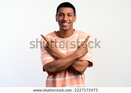 Happy excited young man looking at camera pointing up with fingers hand gesture at copy space advertising new promotion, presenting sale offer standing isolated on white background 