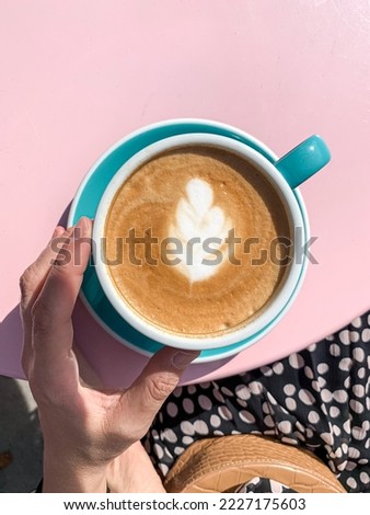 Young woman in silk dress is drinking latte art coffee. Young candid woman drinking morning coffee in tiffany color ceramic mug with saucer on cafe terrace. High quality photo