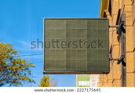 Outdoor empty monitor LED display hanging on building over street.
