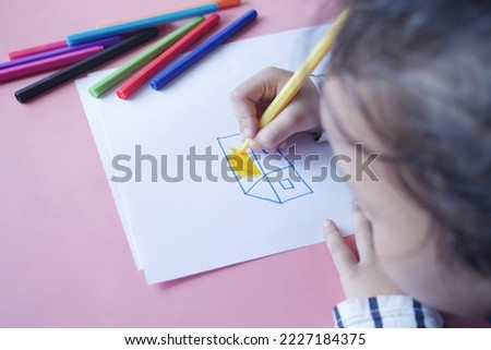 Close up of a child hand drawing with colored pencil on a page.