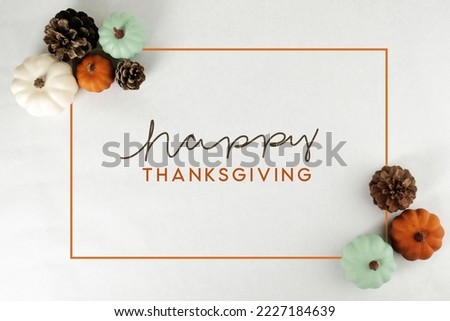 Pumpkins and pinecones from top view with Happy Thanksgiving greeting background.