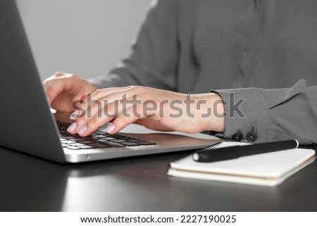 Woman typing on laptop at table, closeup. Electronic document management