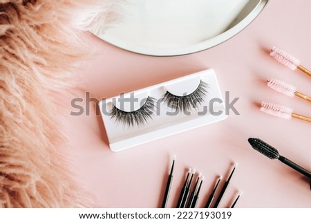 Tools for eyelash extension on trendy pastel pink background. False eyelashes, tweezers and brushes. Beauty shop. Makeup cosmetics. Top view, flat lay.