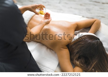Beautician's POV during traditional relaxing oil massage. Beautiful young woman lying lying on her stomach and enjoying her SPA day. Unrecognizable people. High quality photo