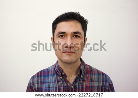 Male mugshot for passport. Serious portrait of adult man for id card. Visa picture. Soft focus. Film grain texture. Korean guy taking picture for papers in studio against white wall.  Royalty-Free Stock Photo #2227218717