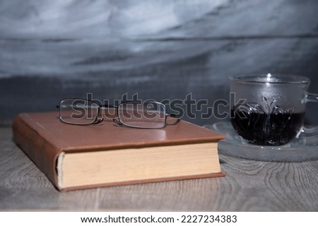 book and glasses on wooden background.