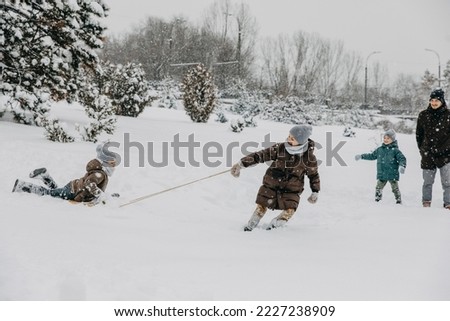 Children playing on snowy winter day. Boy pulling sledge.