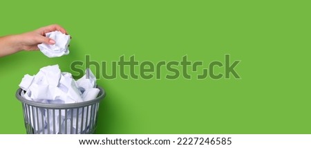 Woman throwing crumpled paper into trash bin on green background with space for text