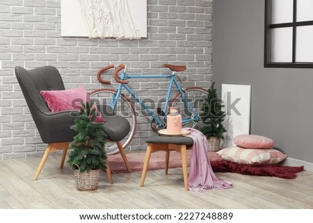 Interior of living room with bicycle, armchair and small fir trees