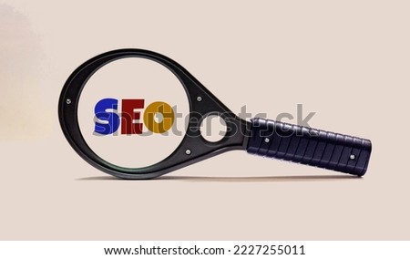 Selective focus of magnifying glass with SEO Search Engine Optimization text on white background.