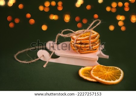 Slice dried oranges on wooden decorative sled, green Christmas background. Bokhe lights. New Year and Christmas time. Weihnachten 