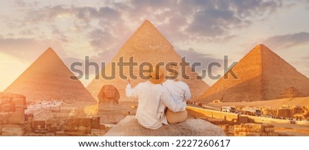 Back view lover couple, Tourists woman and man with hat background Sphinx and pyramid of Egyptian Giza, sunset Cairo, Egypt. Royalty-Free Stock Photo #2227260617