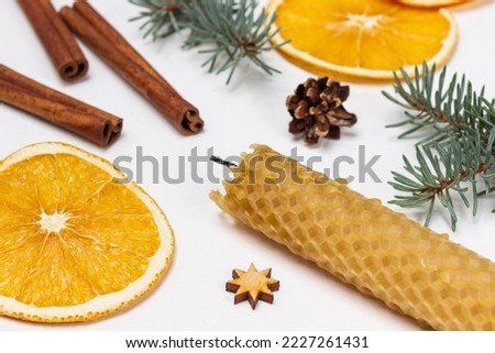 Wax candle, cinnamon sticks and dry orange slices. Top view. White background.