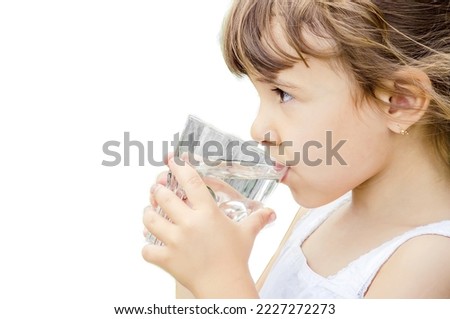 The child drinks water from a glass of isolate. Selective focus. Kid.