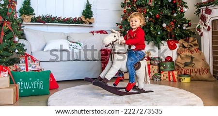 Child on horseback near the Christmas tree. Selective focus. Kid.
