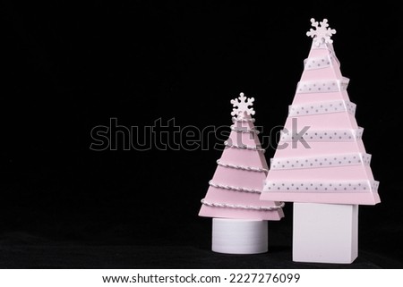 Pink Christmas tree wrapped in white and silver ribbon with white stumps on a black background 