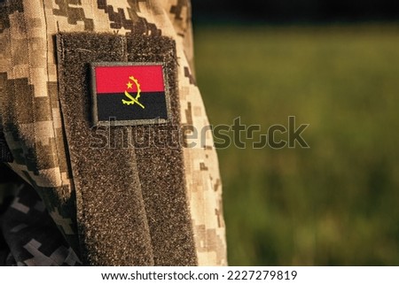 Close up millitary woman or man shoulder arm sleeve with Angola flag patch. Angola troops army, soldier camouflage uniform. Armed Forces, empty copy space for text

