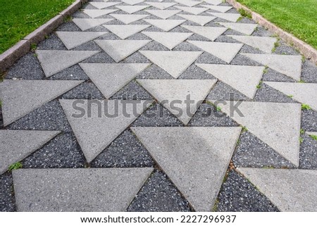 Outdoor asphalt patio with triangular shaped concrete inserts
