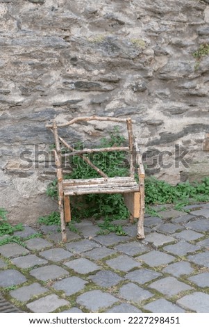 in front of the wall is a small chair made of branches