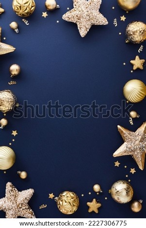Luxury gold Christmas decorations on dark blue table. Elegant Christmas vertical banner design, poster, party invitation template.
Frame of golden balls, stars, confetti. Top view.