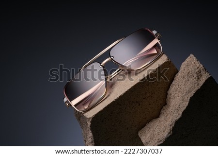 Beautiful sunglasses on a beautiful background with stones. Advertising your glasses. Gold frame glasses for women. Optical shop advertising background Fashion Vintage Style and product promotion Royalty-Free Stock Photo #2227307037