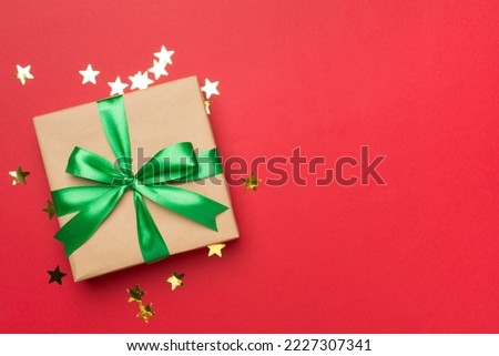 Gift box and stars confetti on color background, top view