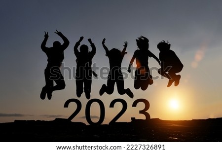 Happy group of people celebrate jump for new year 2023. concept for win victory. silhouette of friends jumps at sunset time on mountains.