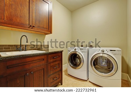 Laundry room with modern appliances, dark brown vanity cabinet with drawers.