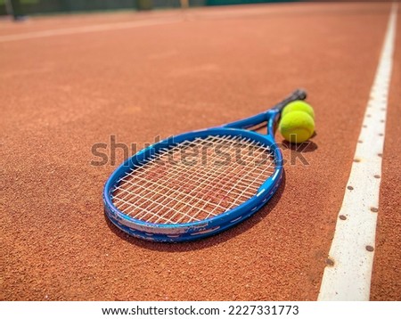Balls and racket are lying on clay brown professional tennis court Close up of tennis balls and racket on dross at tennis court on the playground. Sport concept. Perspective up top view 